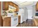 Efficient kitchen layout with wooden cabinets, white appliances, and durable wood-look flooring at 3051 Arrow Wood Ln, Indianapolis, IN 46214