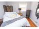Well-lit bedroom features a bed with white linens, hardwood floors, neutral walls, and decorative accents and decor at 311 S Webster Ave, Indianapolis, IN 46219