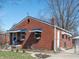 Charming brick home featuring a well-maintained lawn, complemented by blue awnings and a walkway to the entrance at 311 S Webster Ave, Indianapolis, IN 46219