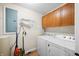 Bright laundry room featuring wood cabinets, white washer and dryer, and organized cleaning supplies at 3875 Offshore Dr, Columbus, IN 47203