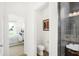 Well-appointed powder room next to a modern glass-enclosed shower and view into the main bedroom at 5035 Astor Ct, McCordsville, IN 46055