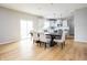 Open-concept dining area with hardwood floors, a large table, and a view of the modern kitchen at 6345 Meadowview Dr, Whitestown, IN 46075