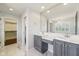 A well-lit bathroom featuring dual vanities, marble floors, and a walk-in closet in the background at 6516 Shamel Dr, Indianapolis, IN 46278
