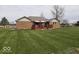 Spacious backyard features a well-manicured lawn, mature trees, and brick house with a wooden deck at 791 W 500 S, Greenfield, IN 46140