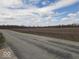 Road leading to a plowed field under a blue sky with scattered clouds at 791 W 500 S, Greenfield, IN 46140