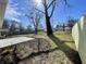 Grassy backyard featuring a large tree, wooden fence, and concrete patio under a sunny sky at 8525 E 42Nd Pl, Indianapolis, IN 46226
