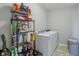Well-organized laundry room featuring modern washer and dryer with shelving for storage and tile flooring at 9723 Violet Cir, Indianapolis, IN 46239