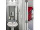 Cozy powder room with pedestal sink, modern mirror, and adjacent to a staircase with red curtains at 9723 Violet Cir, Indianapolis, IN 46239