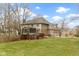View of the home's backyard with a deck, enclosed porch, green lawn, and mature trees at 9931 Woodlands Dr, Fishers, IN 46037