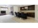 Basement wet bar with seating, dark cabinets, and view of the brick fireplace at 9931 Woodlands Dr, Fishers, IN 46037