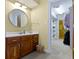 Bathroom with a wooden vanity, round mirror, closet access, and white countertop at 9931 Woodlands Dr, Fishers, IN 46037