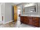 Well-lit bathroom featuring a wooden vanity, framed mirror, and wood-look flooring at 9931 Woodlands Dr, Fishers, IN 46037