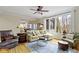 Bright living room with a ceiling fan, hardwood floors, area rug, and a comfortable sofa with natural light from the large window at 9931 Woodlands Dr, Fishers, IN 46037