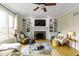 Sunlit living room showcasing hardwood floors, a ceiling fan, and a fireplace at 9931 Woodlands Dr, Fishers, IN 46037