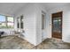 The sunroom features neutral colors, three chairs, and a wooden front door to welcome guests at 1655 Cornell Ave, Indianapolis, IN 46202