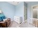 Well-lit blue bedroom with a crib, white dresser, and a cozy leather chair with throw at 1665 N College Ave, Indianapolis, IN 46202