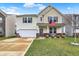 Inviting two-story home with a well-manicured lawn, front porch with decorative plants, and an attached two-car garage at 2282 Creekland Dr, Columbus, IN 47201