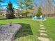 Well-maintained backyard with a firepit area surrounded by Adirondack chairs, stepping stones, and lush greenery at 3610 Eagle Emblem Ct, Greenwood, IN 46143