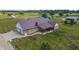 An aerial view captures a brick home with metal roof, a patio, an attached garage, and verdant surroundings at 3777 S 300 E, Anderson, IN 46017
