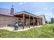 Inviting covered patio with wood columns, a hot tub, comfortable seating, and a cozy outdoor fireplace, perfect for relaxing at 3777 S 300 E, Anderson, IN 46017