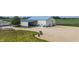 Large metal building with covered parking, a large garage door, and additional outbuilding on a gravel lot at 3777 S 300 E, Anderson, IN 46017