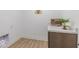 Bright laundry room featuring wood-look floors, white walls, and a stylish wooden cabinet at 4738 E Shadowbrook Dr, Camby, IN 46113