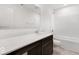 Bathroom featuring a long quartz countertop, dark cabinets, neutral tile floors, and tub with white tile walls at 4739 E Shadowbrook Dr, Camby, IN 46113