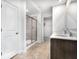 Bathroom featuring a double vanity with dark cabinets, neutral tile floors, and glass-enclosed shower at 4739 E Shadowbrook Dr, Camby, IN 46113
