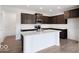 Modern kitchen with dark wood cabinets, a white island with sink, stainless steel appliances and wood floor at 4739 E Shadowbrook Dr, Camby, IN 46113