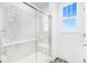 Walk-in shower with white marble-patterned tiles and glass door, complemented by a window for natural light at 5771 Cr W 750 N, McCordsville, IN 46055