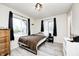Bright bedroom with wood-look floors, two windows with black curtains, and a black metal bed frame at 5984 Williams Dr, Plainfield, IN 46168