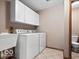 Functional laundry room with washer, dryer, sink, storage cabinets and tile flooring at 6744 Robin Hood Ct, Indianapolis, IN 46227
