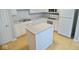 Well-lit kitchen showcasing white cabinetry, an island, modern appliances, and laminate flooring at 788 Tulip Ln, Greenwood, IN 46143