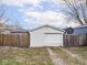 View of detached one car garage featuring white painted siding and an asphalt driveway, surrounded by a wooden fence and grass at 928 E Pleasant Run Parkway North Dr, Indianapolis, IN 46203