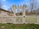 Backyard featuring a pergola-covered gate and a white picket fence, creating an inviting outdoor space at 1418 E Maple Dr, Shelbyville, IN 46176