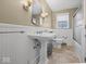 Clean and bright bathroom with a pedestal sink, wainscoting, and tile flooring at 1418 E Maple Dr, Shelbyville, IN 46176