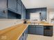 A well-lit kitchen with wood countertops, blue cabinetry, and stainless steel sink at 1418 E Maple Dr, Shelbyville, IN 46176