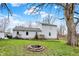 Spacious backyard features green grass, mature trees, a brick fire pit, and a raised deck attached to the home at 207 E Ohio St, Mooresville, IN 46158