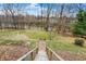View of a large yard with wooden stairs leading down to a waterway, trees, and greenery at 207 E Ohio St, Mooresville, IN 46158