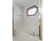Close-up of a marble bathtub with gold fixtures and a unique window letting in natural light at 2437 W Wavelyn N Cir, Martinsville, IN 46151