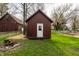 There is an outbuilding with a white door, adjacent to a larger building with a pile of wood in the yard at 4610 W 72Nd St, Indianapolis, IN 46268