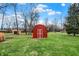 View of backyard with a red storage shed and mature trees at 6611 Valley Mills Ave, Indianapolis, IN 46241