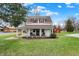 A picturesque two-story home featuring a red barn, a covered porch, manicured lawn, and lush trees, evoking a serene country charm at 6611 Valley Mills Ave, Indianapolis, IN 46241