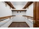 Spacious walk-in closet with wooden shelving and hanging rods, and neutral-colored carpet at 6628 Moss Cir, Indianapolis, IN 46237
