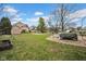 A backyard scene featuring grass, a shed, basketball court, and surrounding houses at 7383 Poppyseed Dr, Indianapolis, IN 46237