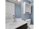 Cozy bathroom with blue walls featuring a white vanity, sink, and cabinet with modern fixtures and lighting at 7383 Poppyseed Dr, Indianapolis, IN 46237