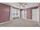 Bedroom features mauve-colored walls, carpeted floors, a ceiling fan, and natural light from a window at 7383 Poppyseed Dr, Indianapolis, IN 46237