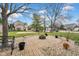 Landscaped brick firepit area with circular design, gravel border, black bench, and manicured lawn at 7383 Poppyseed Dr, Indianapolis, IN 46237