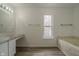 An airy bathroom featuring a window, bath tub and vanity with laminate wood flooring at 10309 Buckshire Ln, Indianapolis, IN 46234