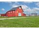 Exterior view of a large red barn with silos in the background, set against a blue sky, surrounded by green fields at 10573 W 550 N, Thorntown, IN 46071